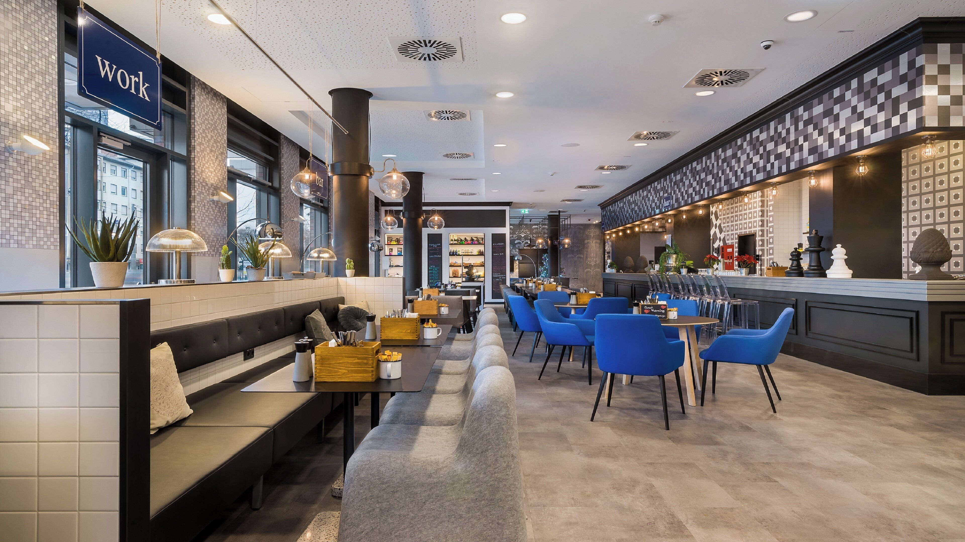 Zona bar moderna con posti a sedere e un cartello con la scritta 'work'.