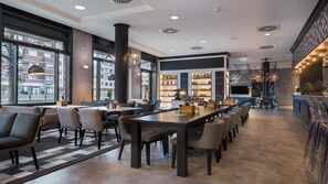 A modern restaurant with a bar area, seating arrangements, and a view of the street outside.