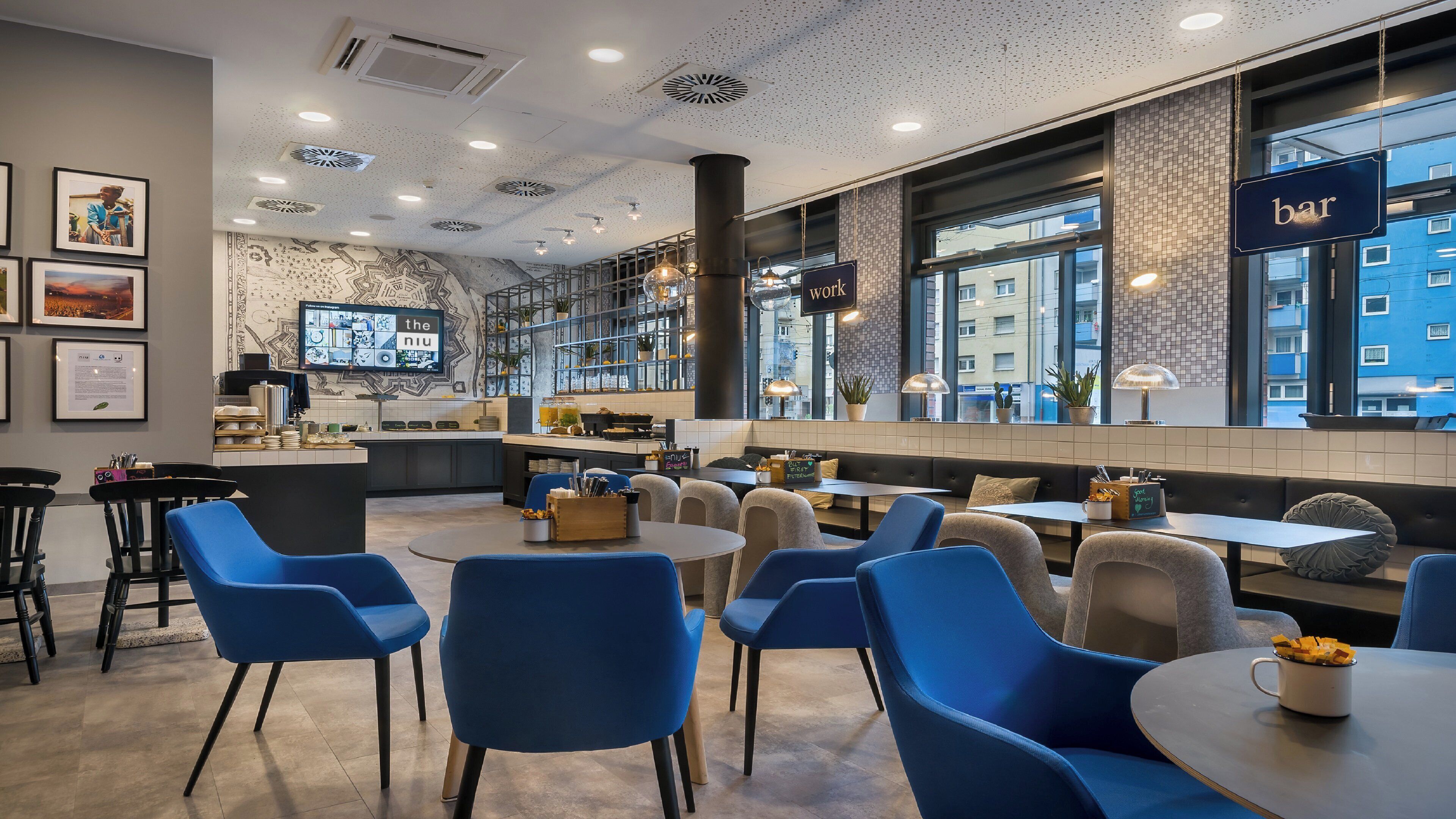 A modern cafe with blue chairs, tables, and a bar area.