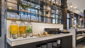Un área de cocina moderna con barra americana, exhibición de frutas y estación de café.