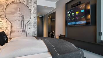 Una habitación de hotel moderna con una cama grande, un televisor integrado en la pared mostrando información de la habitación y un diseño de papel tapiz único.