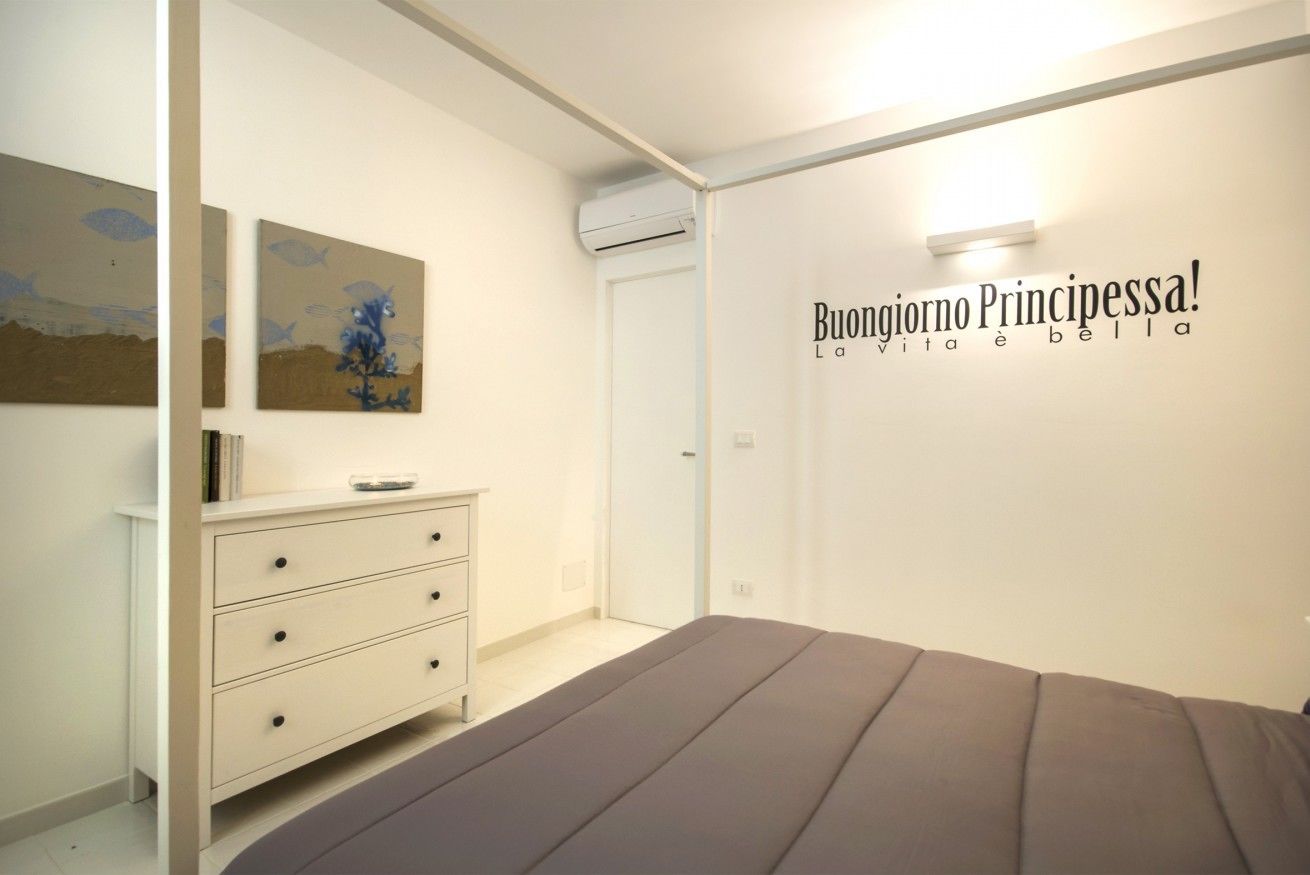 Une chambre à coucher avec un lit, une commode et des œuvres d’art murales.