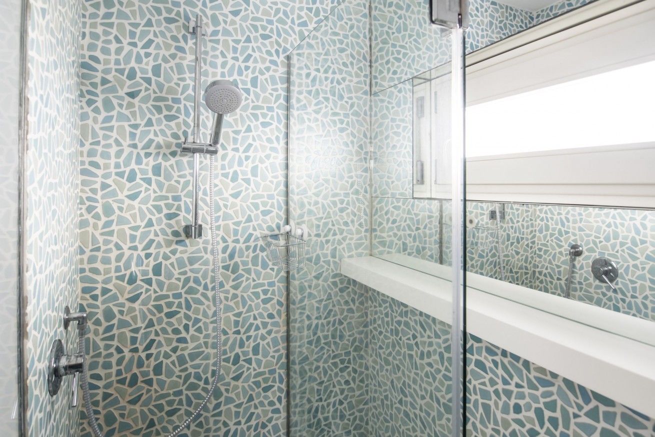 Una ducha con paredes de azulejos decorativos y puerta de vidrio.