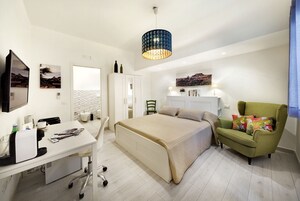 Un dormitorio moderno con cama, escritorio, silla y sofá.