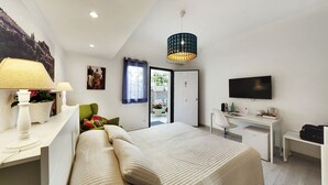 Quarto de hotel moderno com cama, escrivaninha e televisão.