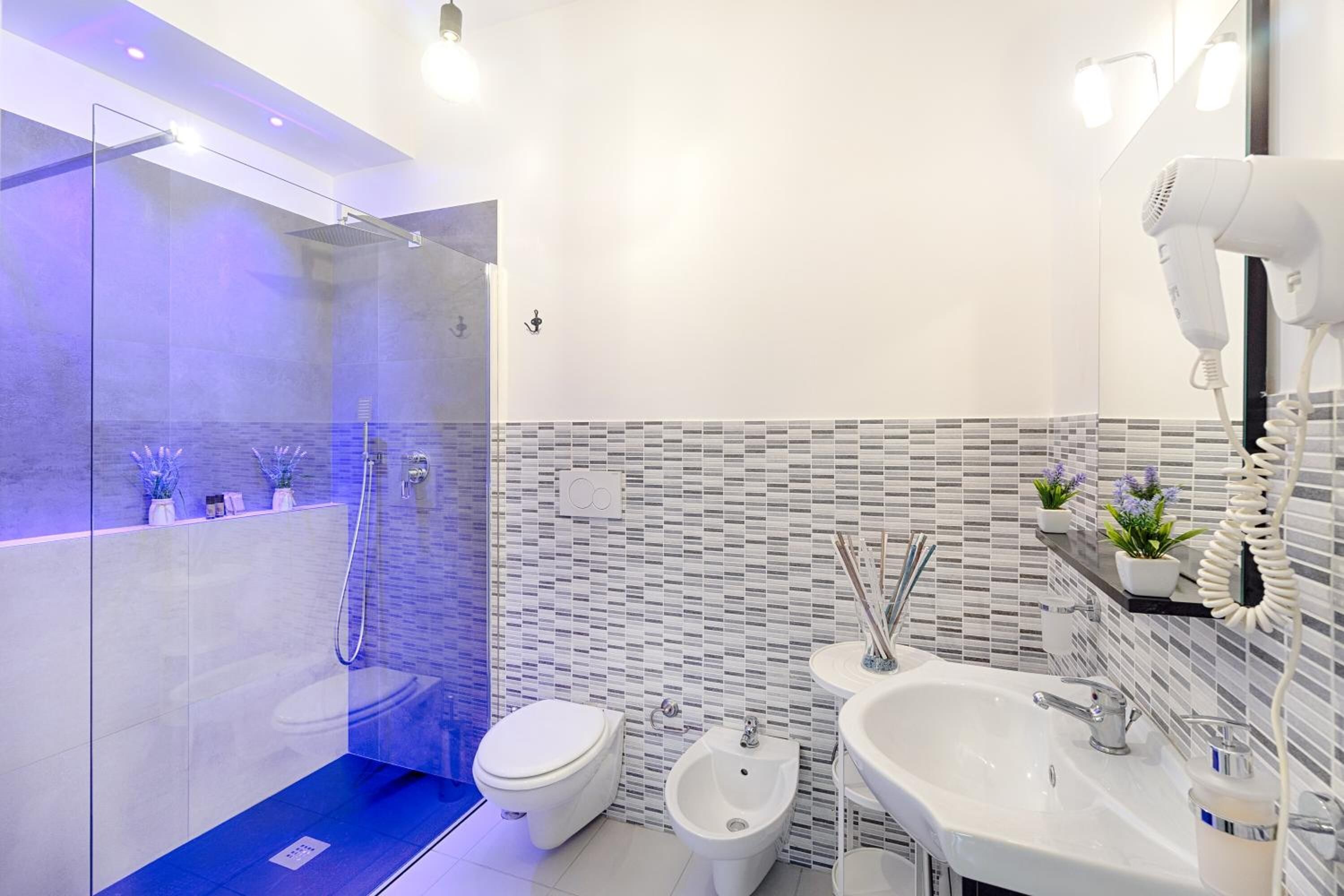 A modern bathroom with a glass-enclosed shower, a bidet, a toilet, and a sink with a mirror.