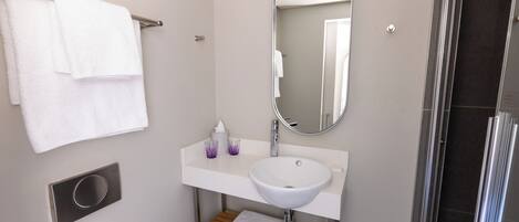 Un baño moderno con lavamanos, espejo y toallero blancos.