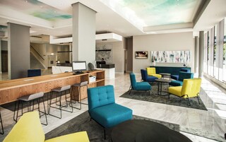 A modern lobby with a reception desk, bar seating, and colorful chairs.