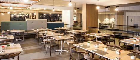 Un interior de restaurante moderno con varias mesas y cabinas, suelo de madera e iluminación colgante.