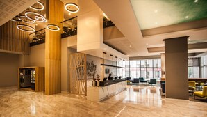Eine moderne Lobby mit Marmorboden, einer Rezeption und einer Sitzecke mit Stühlen.