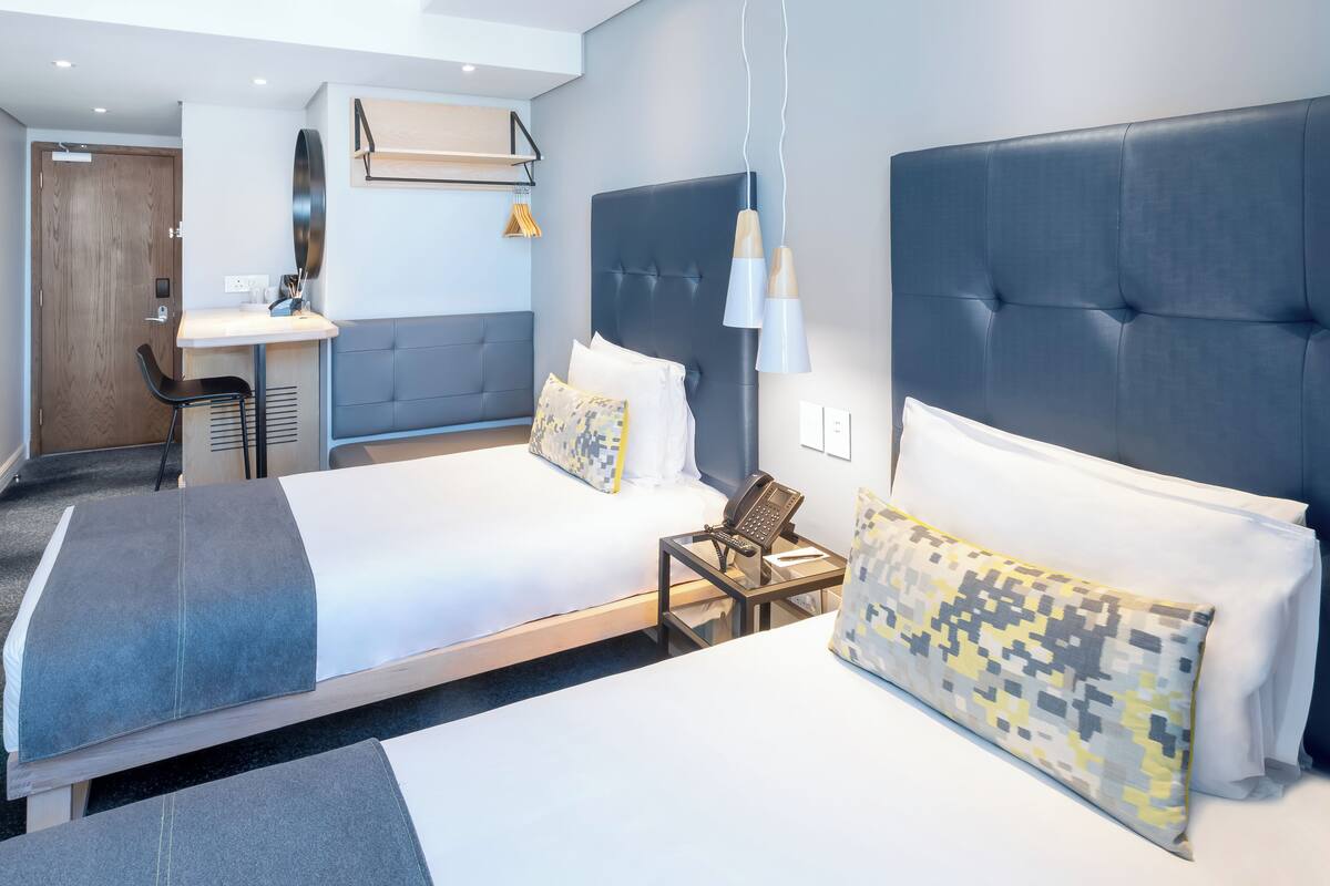 Une chambre d’hôtel moderne avec deux lits, un bureau et une chaise.