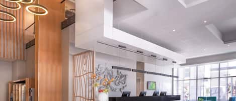 A modern reception area with a marble counter, a wooden reception desk, and a large window offering a view of the city.