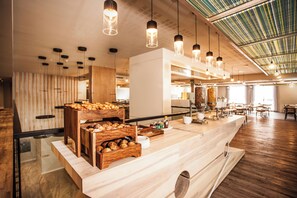 Un comptoir de petit-déjeuner moderne, doté de présentoirs en bois et de luminaires suspendus.