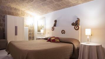 Ein Schlafzimmer mit einem großen Bett, einem Kleiderschrank, einem runden Tisch mit Lampe und Wanddekoration.
