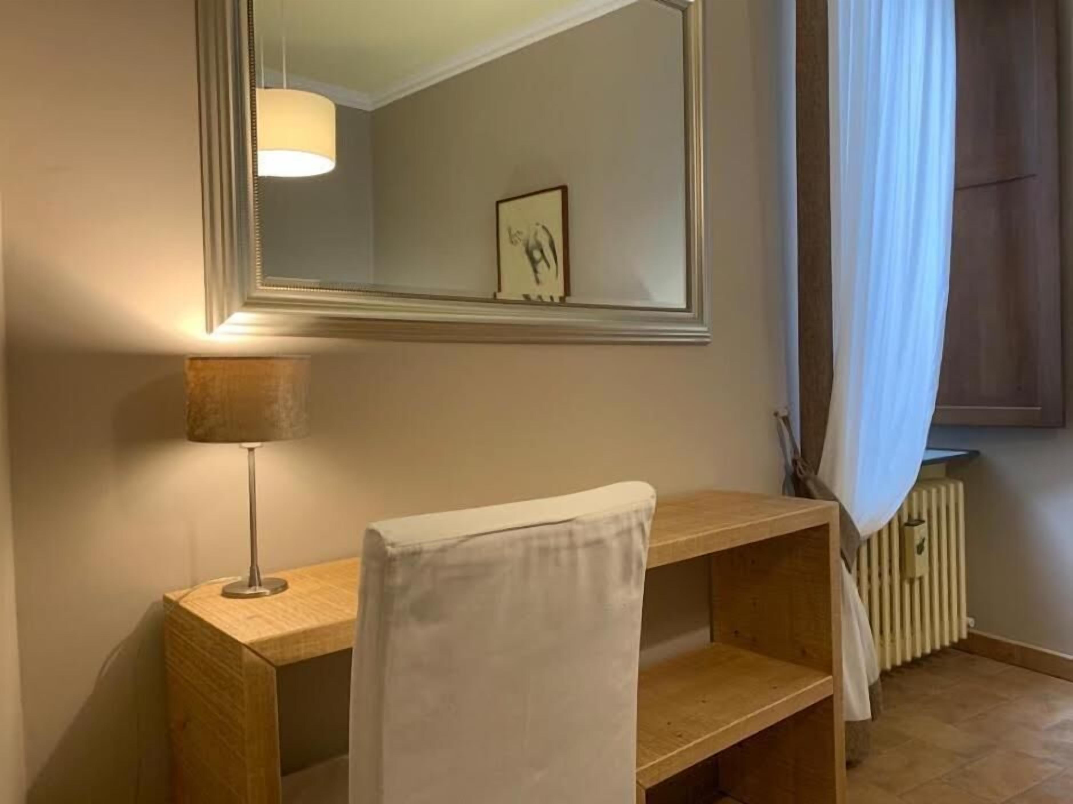 Un bagno con un mobile vanitario in legno, uno specchio, un asciugamano, una lampada e un termosifone.