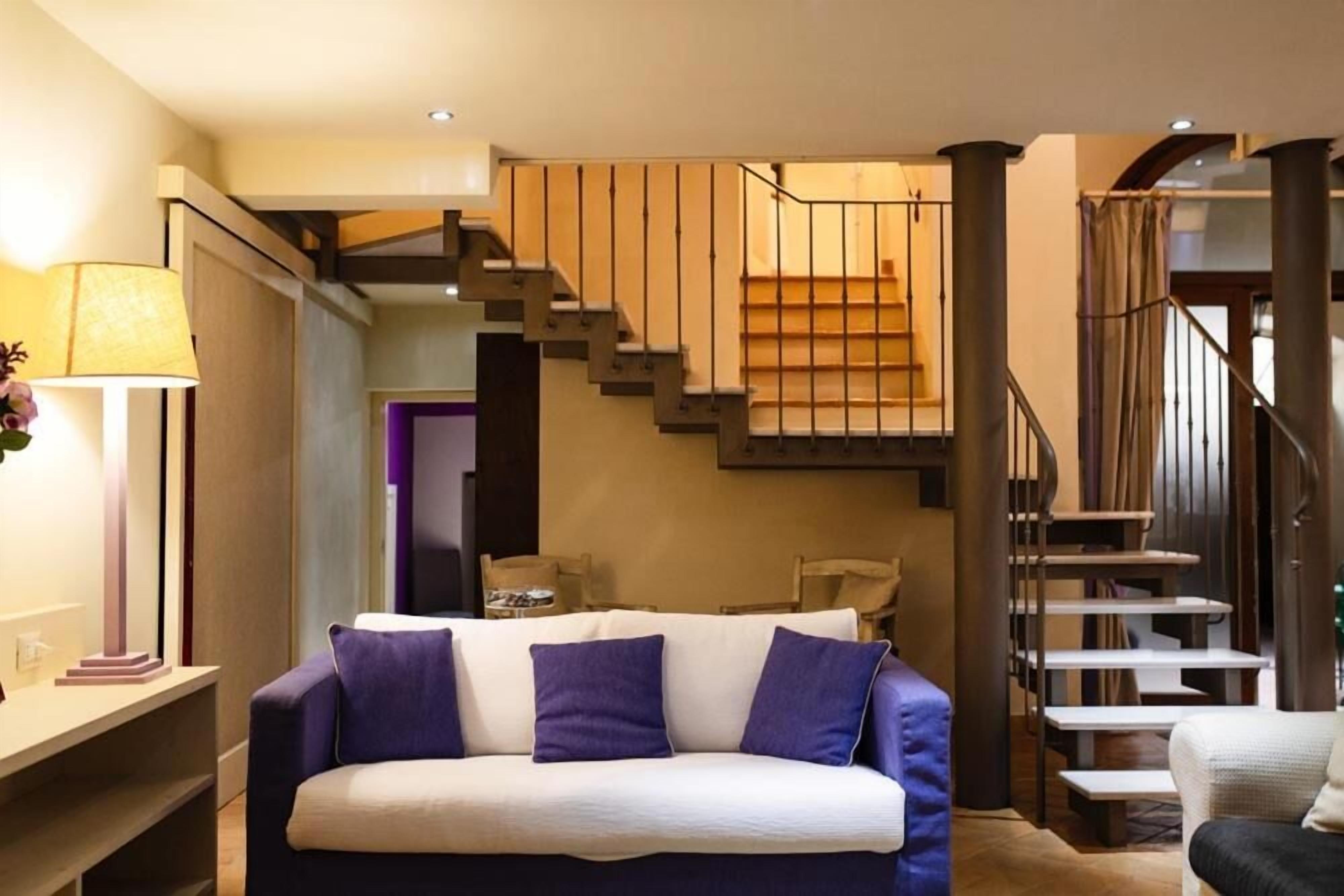 A modern living room with a sofa, a lamp, and a staircase.