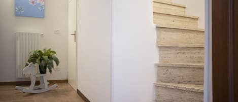 A staircase with beige steps, a white door, and a wall-mounted radiator.