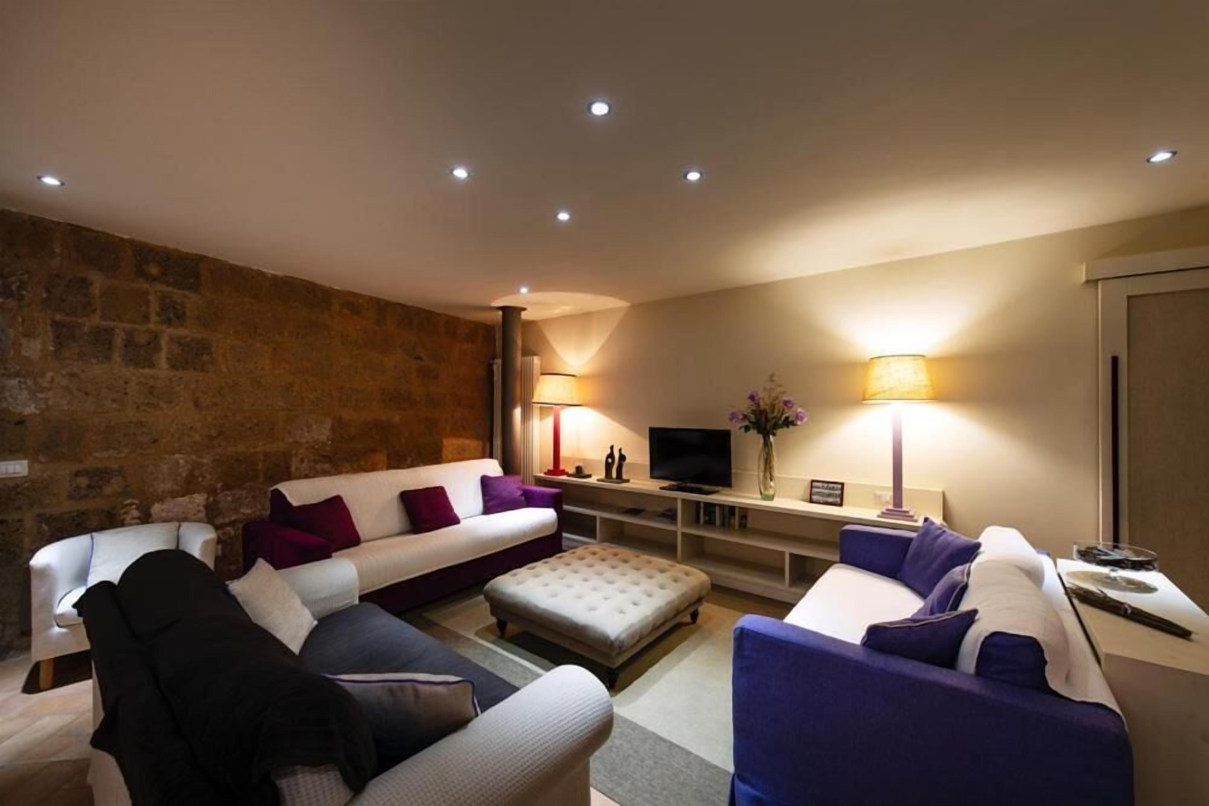 Una sala de estar moderna con una pared de acento de piedra, un sofá modular, una mesa de centro y un televisor.