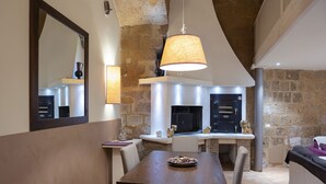 Une cuisine moderne avec des murs en pierre, une table à manger avec des chaises et un luminaire suspendu.