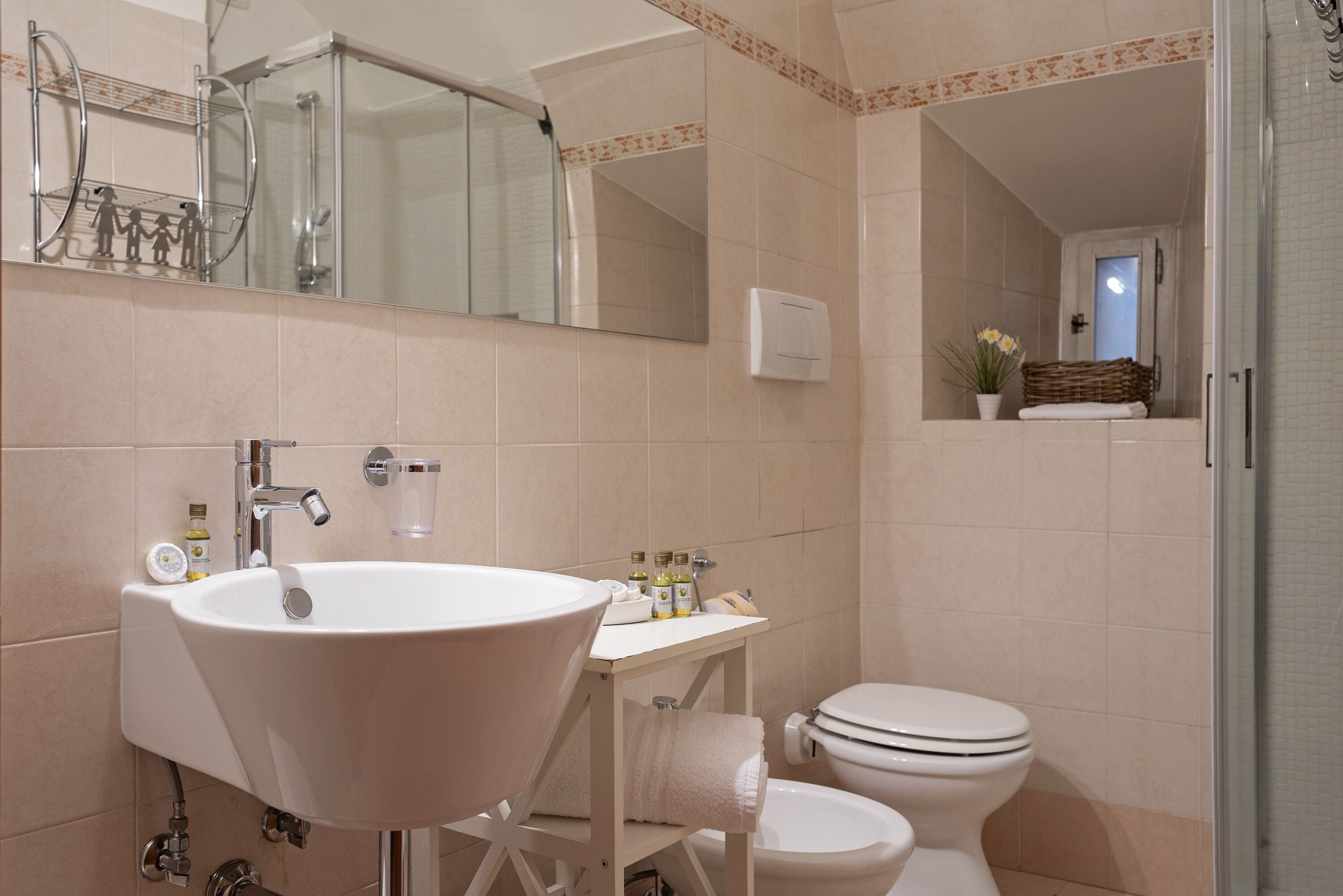 A bathroom with a sink, mirror, toilet, and shower.