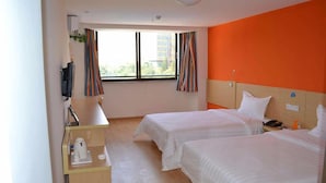 Ein Hotelzimmer mit zwei Betten, einem Schreibtisch und einem Fenster mit Vorhängen.