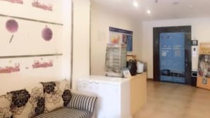 Ein Empfangsbereich mit einer Couch, einer Rezeption und einer Tür im Hintergrund.