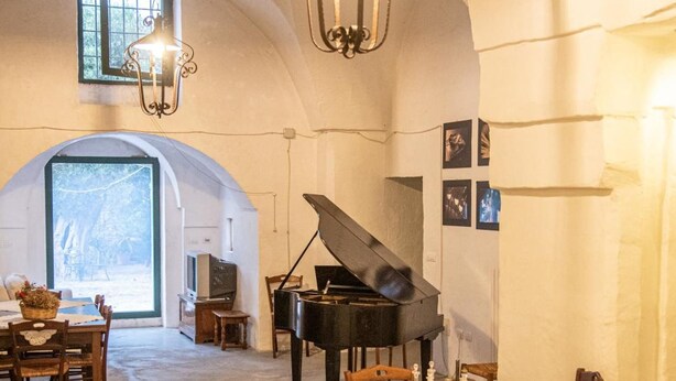 Ein Essbereich mit Klavier, Tischen, Stühlen und einer Chandelier.