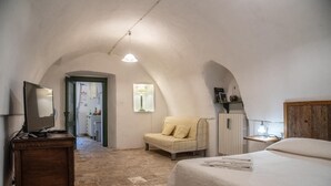 Ein Schlafzimmer mit einem Bett, einem Sessel, einem Schreibtisch und einem Fernseher.