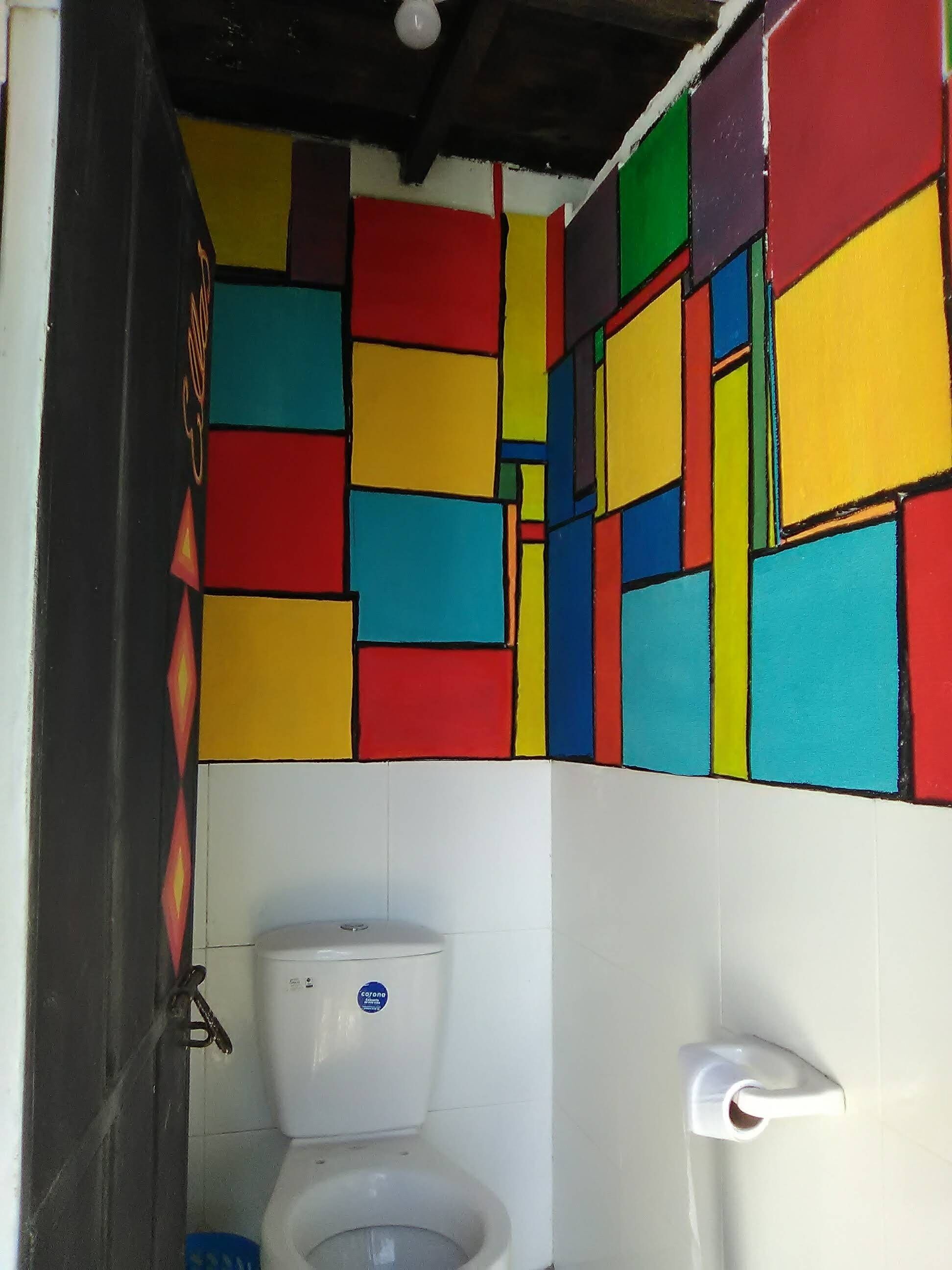 Un baño con una pared de azulejos geométricos de colores y un inodoro blanco.
