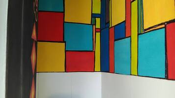 Un baño con una pared de azulejos geométricos de colores y un inodoro blanco.