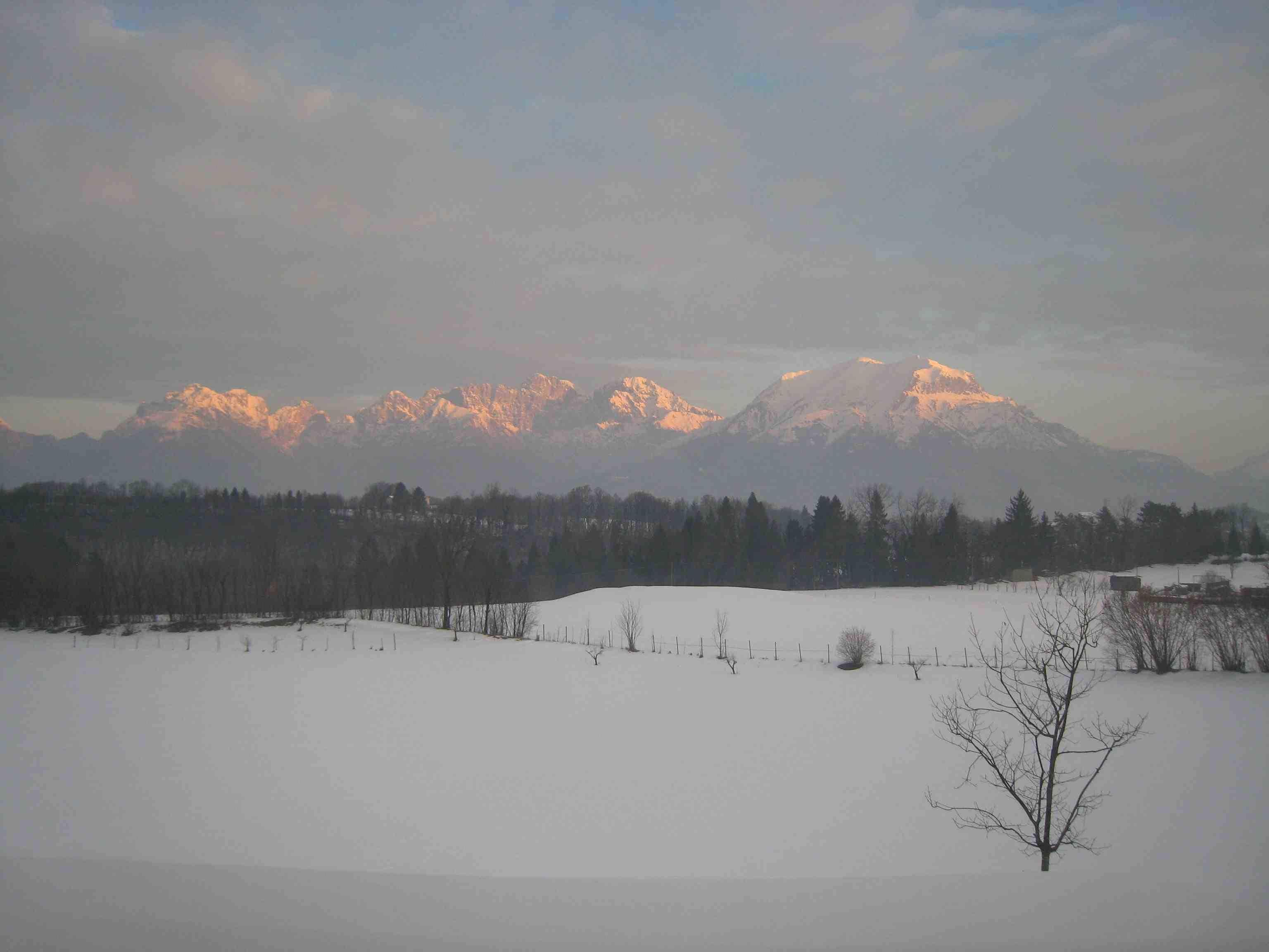 Paesaggio innevato con una catena montuosa sullo sfondo.