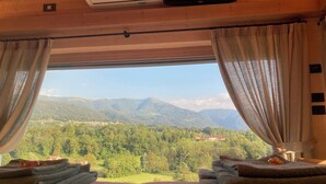 Une chambre avec un lit, deux serviettes, un climatiseur et une fenêtre avec des rideaux.