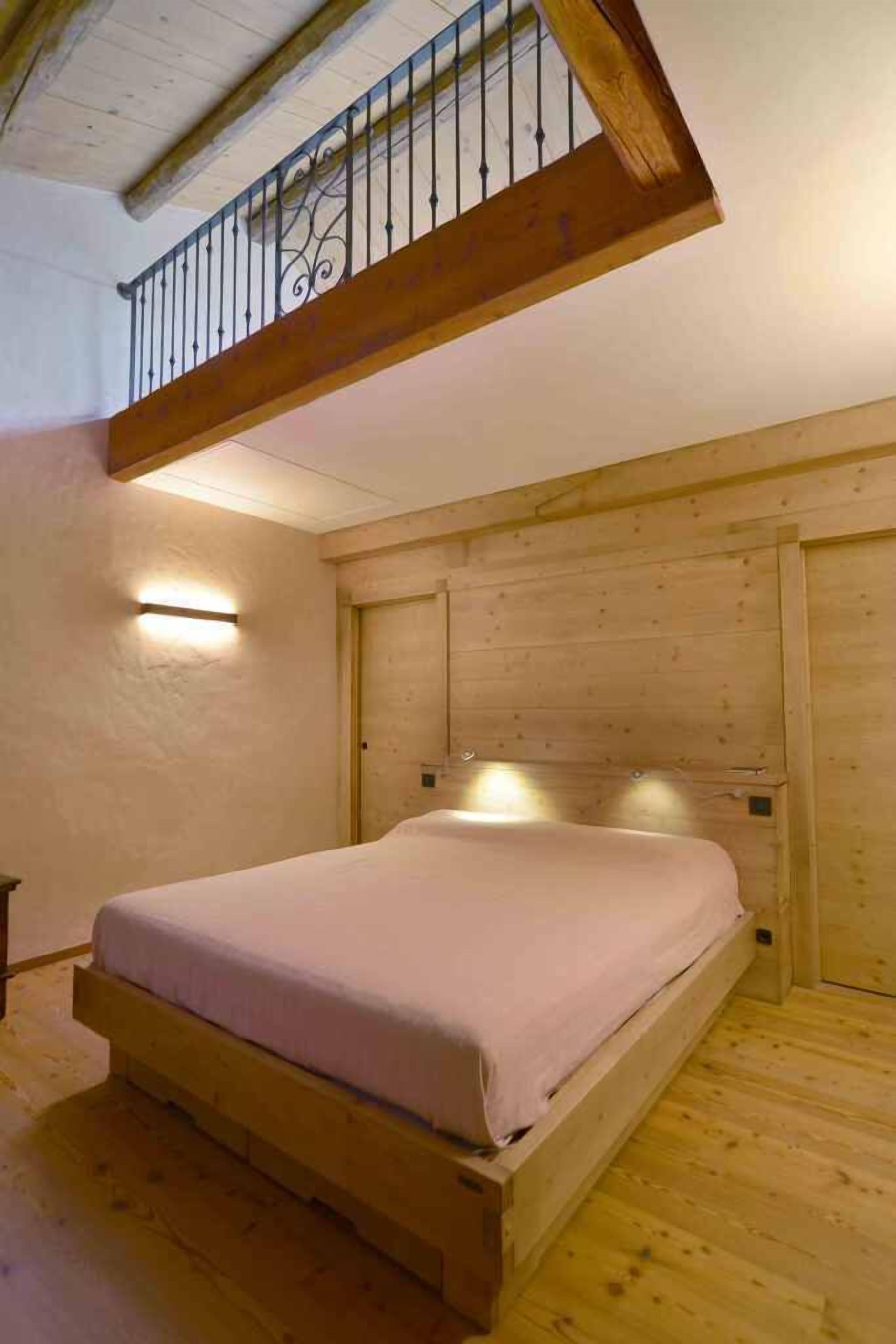 Un lit simple dans une pièce aux murs en bois et au plafond en pente.