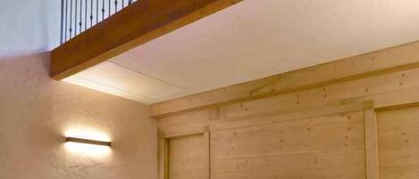 Un lit simple dans une pièce aux murs en bois et au plafond en pente.