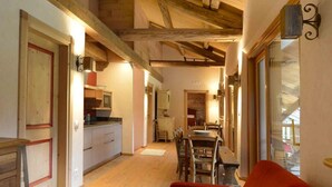Un intérieur chaleureux avec un plafond en bois, un canapé rouge et un coin repas comprenant une table et des chaises.