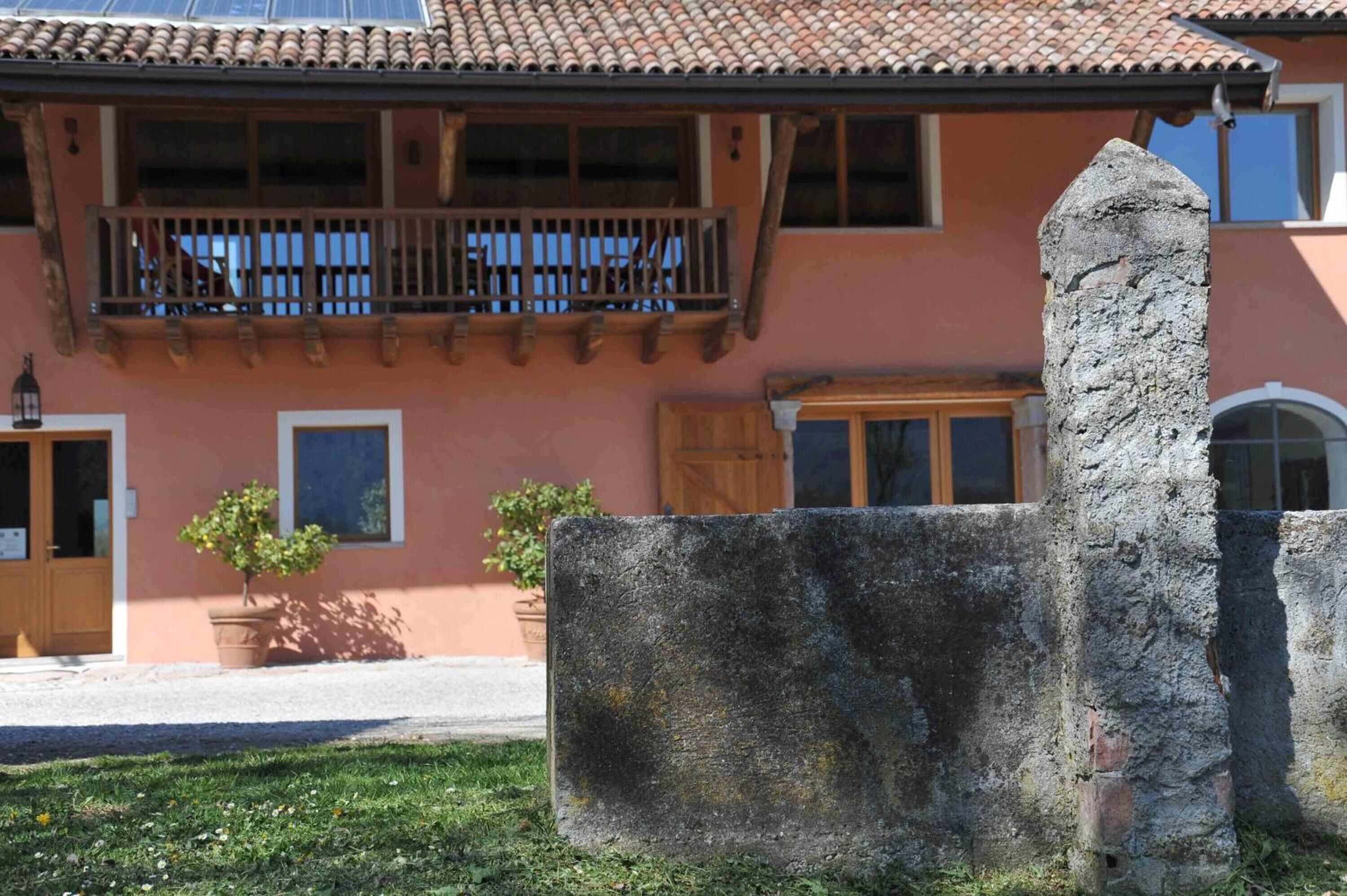 A traditional building with a balcony, a stone wall, and a potted plant.