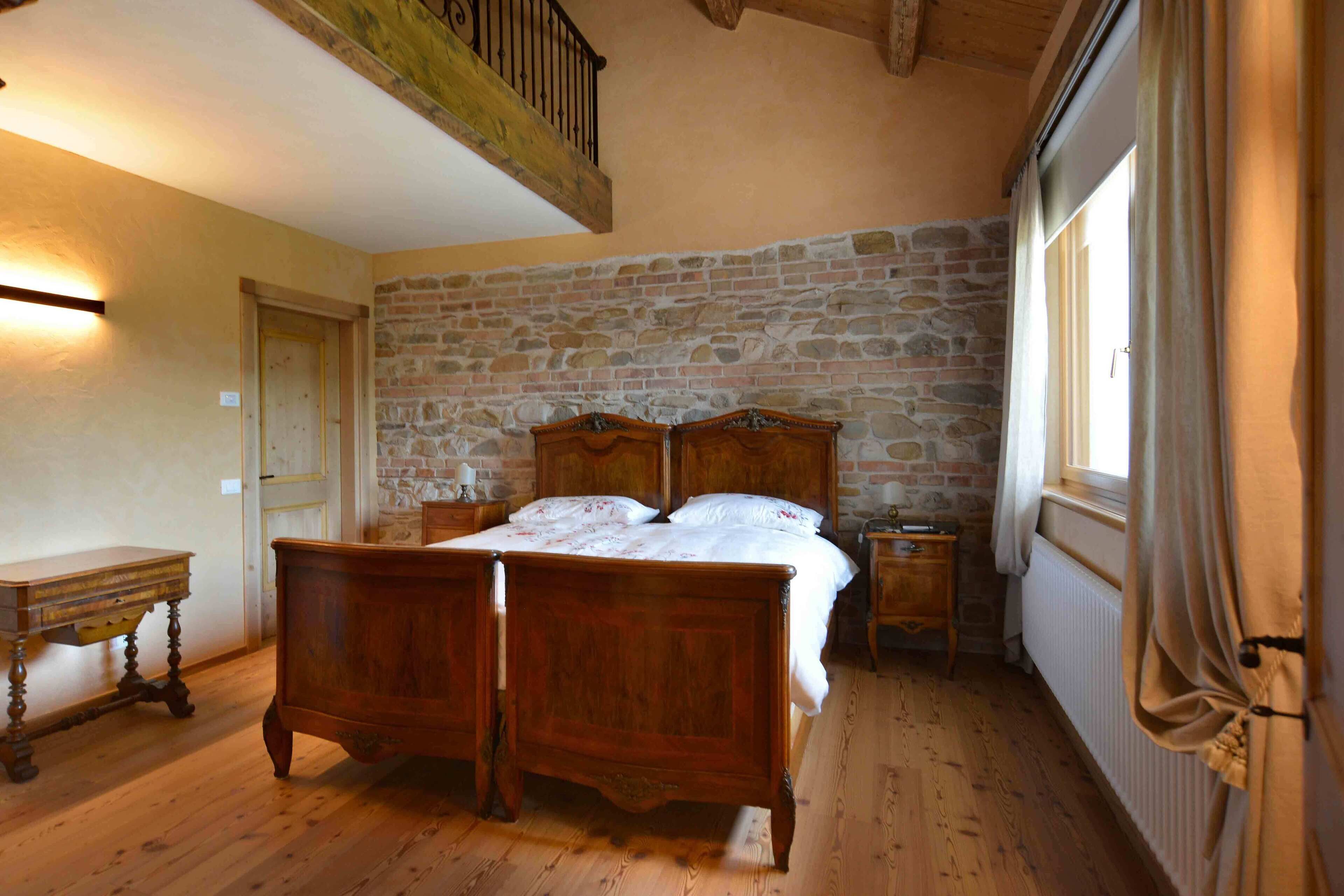Een slaapkamer met een stenen muur, een houten bed en een kleine tafel.