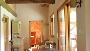 Une table à manger en bois, des chaises, un mur en pierre et un plafond en bois.