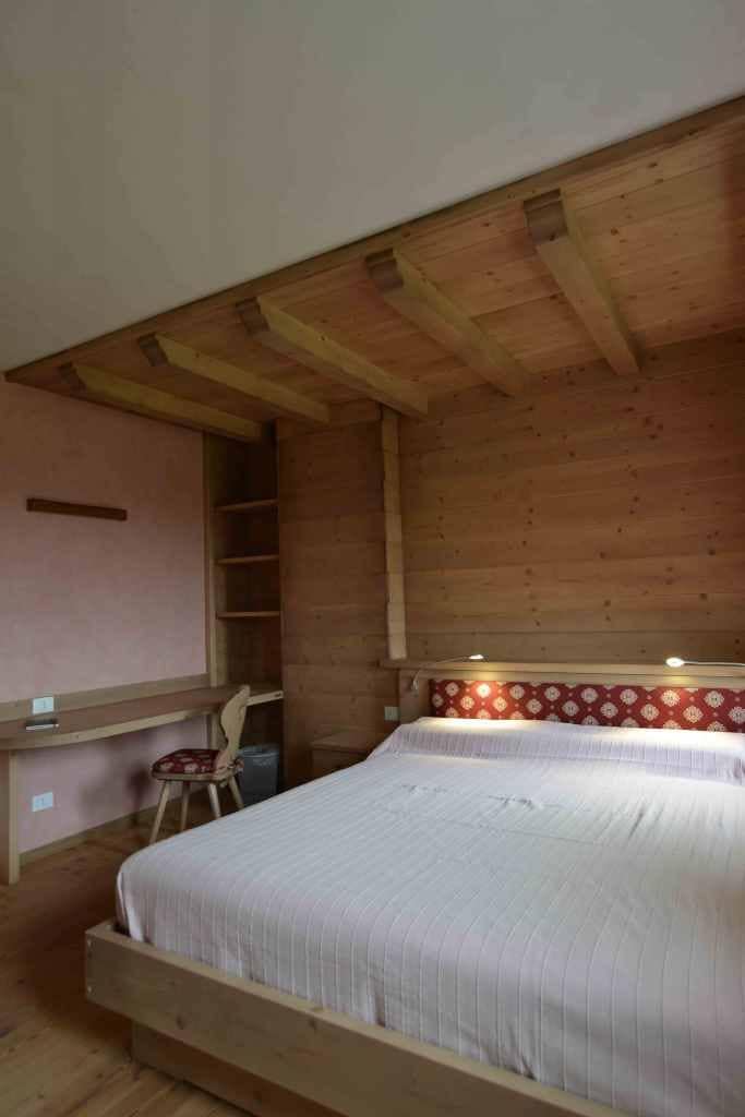 Una cama individual en una habitación con paredes de madera y techo inclinado.