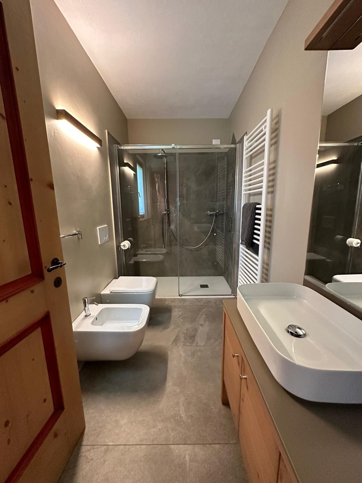 Un bagno moderno con doccia vetrata, due lavabi e uno specchio grande.