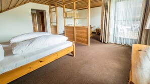 A room with a wooden bed, a desk, and a window with curtains. - Seehotel Weissensee (Fuessen)