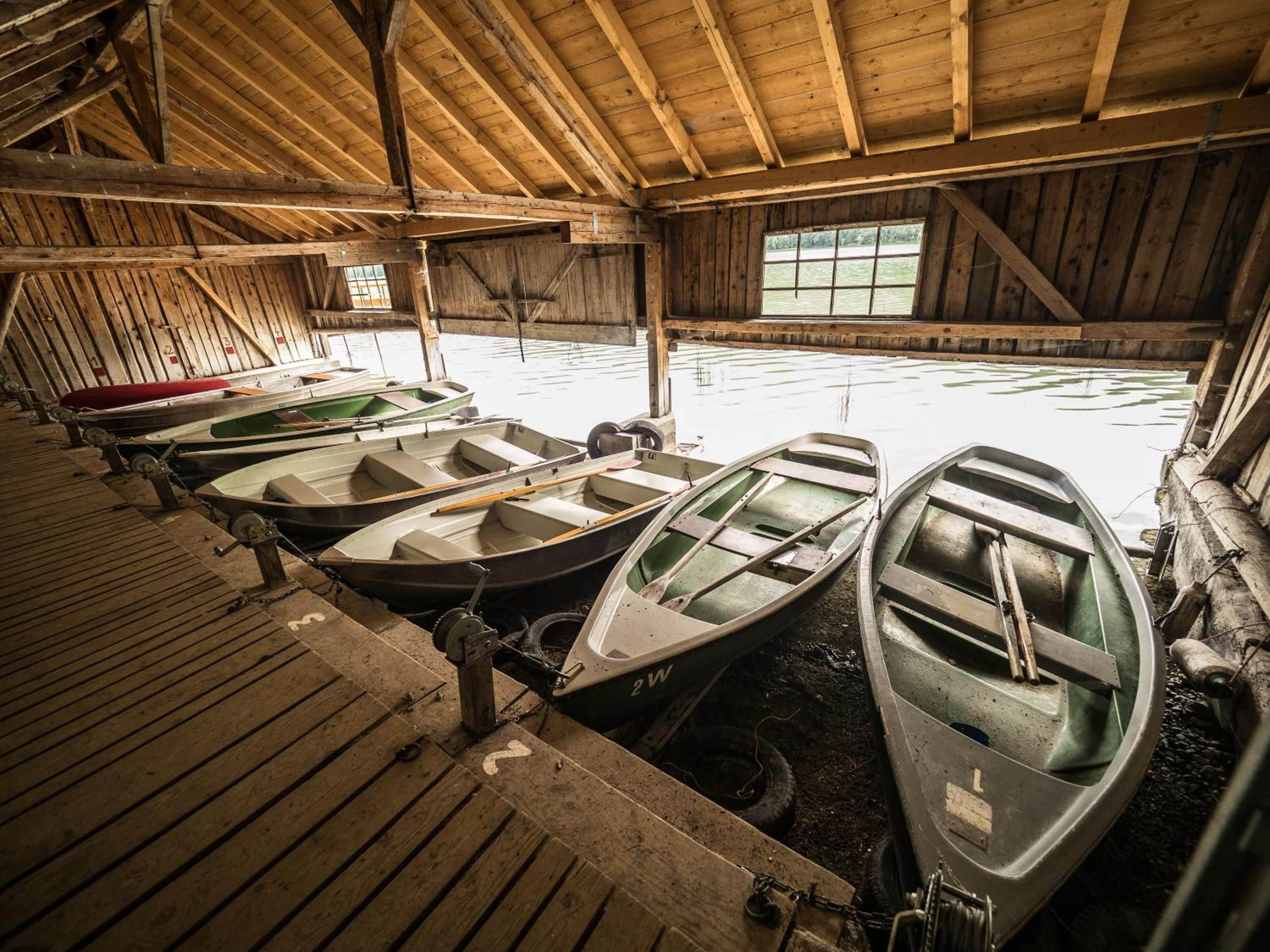 A covered boathouse with several rowboats docked inside.