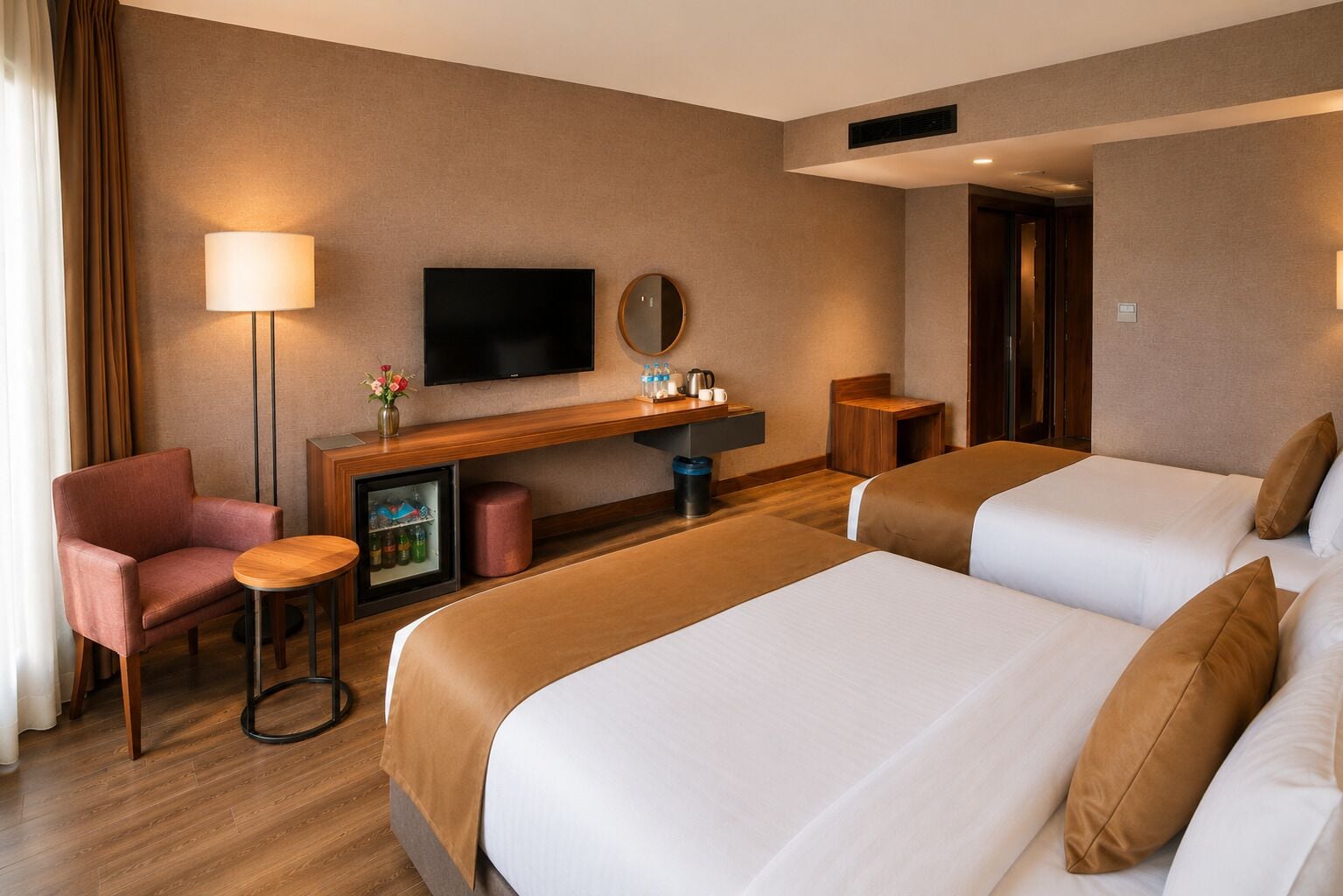 Una habitación de hotel con dos camas, un escritorio con televisor, una silla y una mesita.