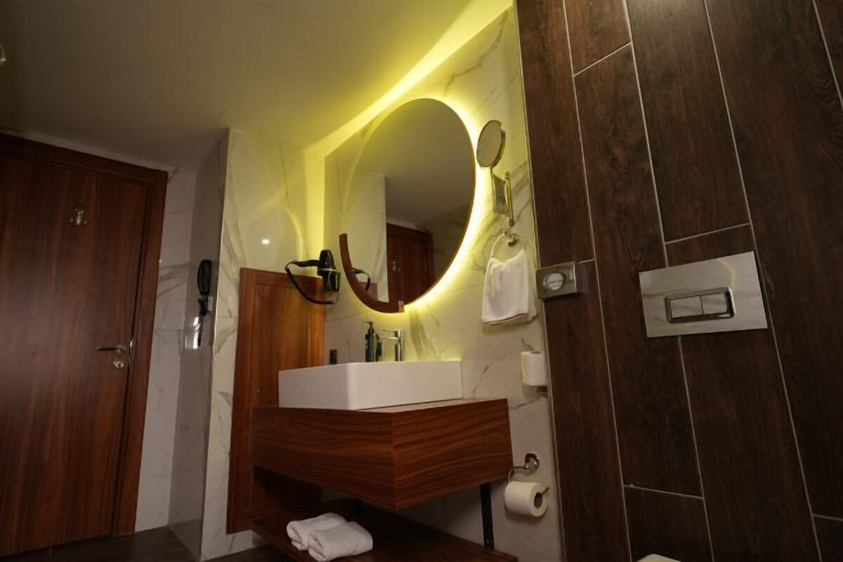 A modern bathroom with a wooden vanity, a large mirror, and a built-in sink.