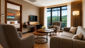 A modern hotel room with a sofa, armchairs, a coffee table, a flat-screen TV, and a balcony with a scenic view. - Hilas Thermal Resort & Spa Aquapark (Ladik)