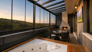 A room with a large window, a fireplace, a hot tub, and a dining area. - Hilas Thermal Resort & Spa Aquapark (Ladik)