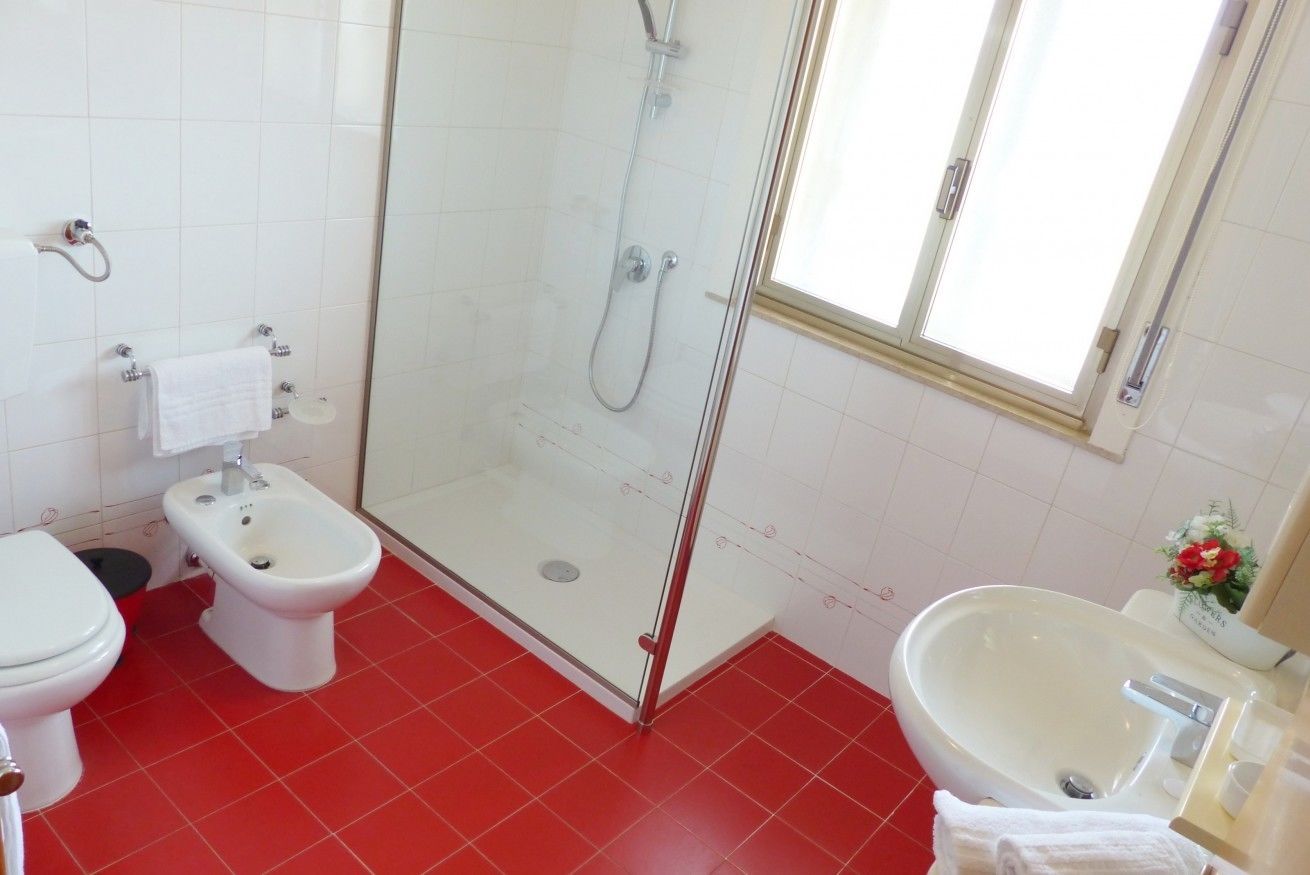 Un bagno con WC, bidet, cabina doccia in vetro e lavandino.