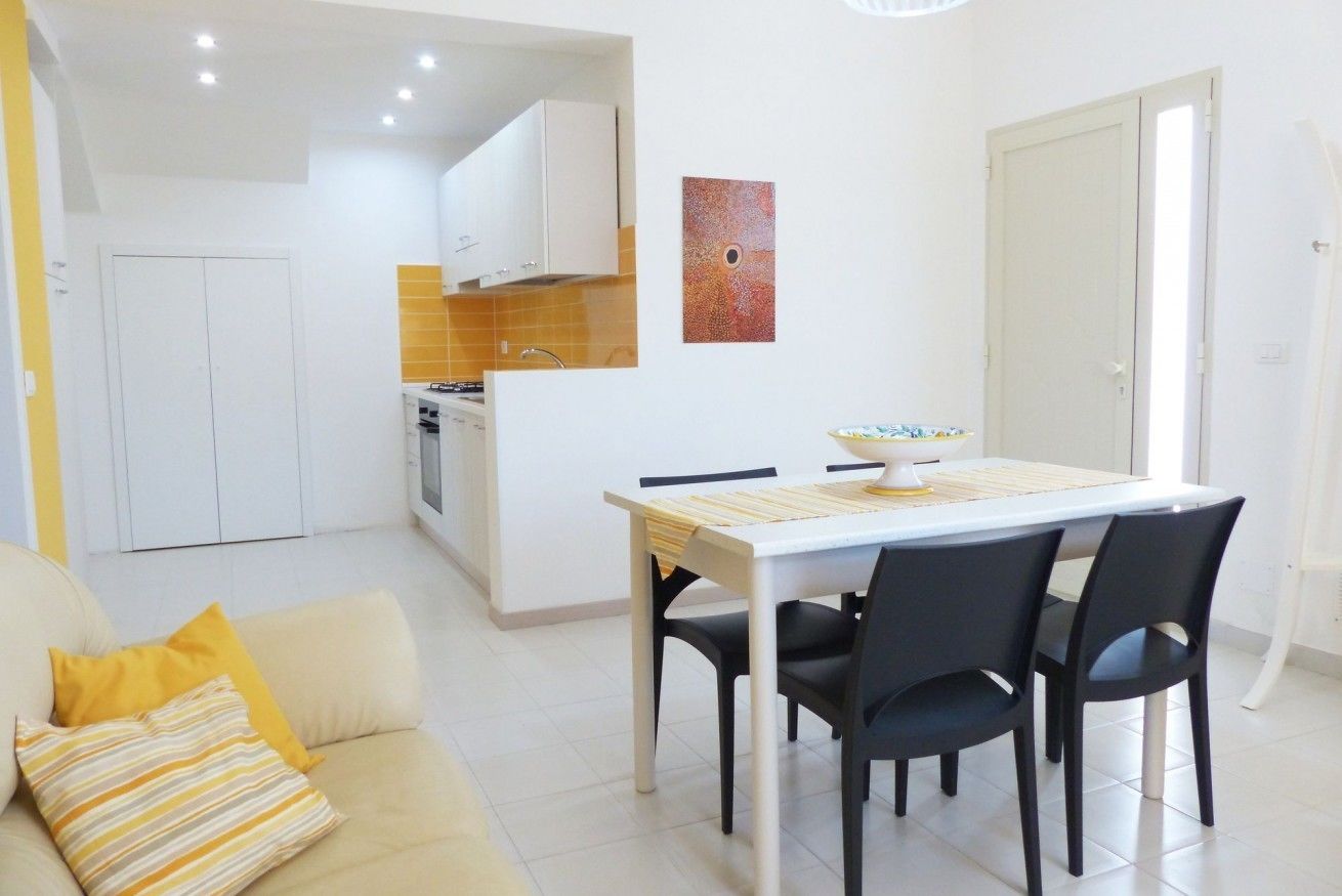 Un apartamento moderno con comedor, cocina y sala de estar con sofá y cojines.