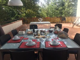 Un área de comedor al aire libre con mesas dispuestas para una comida, rodeada de sillas y una valla de madera.