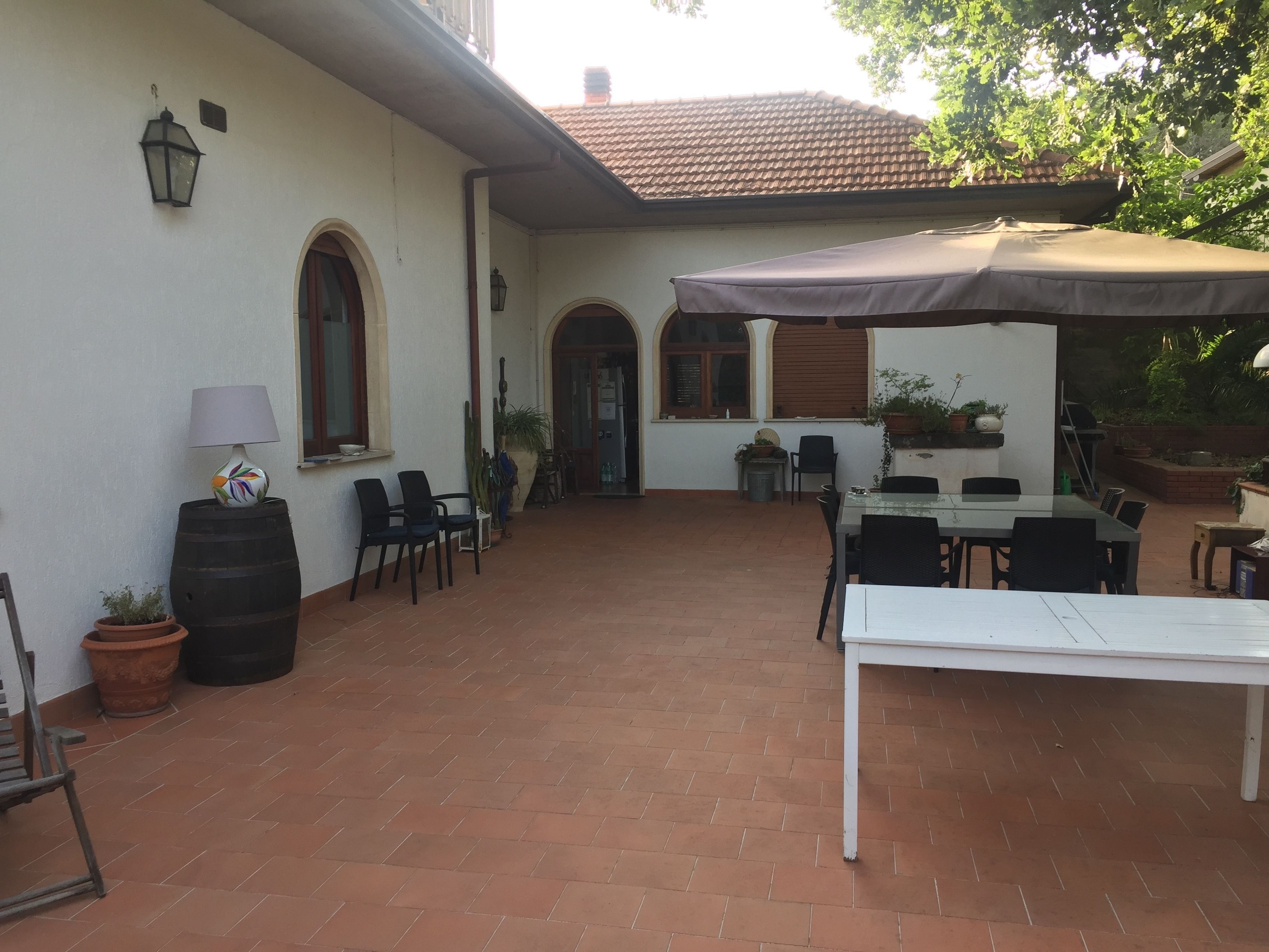 Un patio al aire libre con mesa, sillas, una lámpara y plantas en macetas.